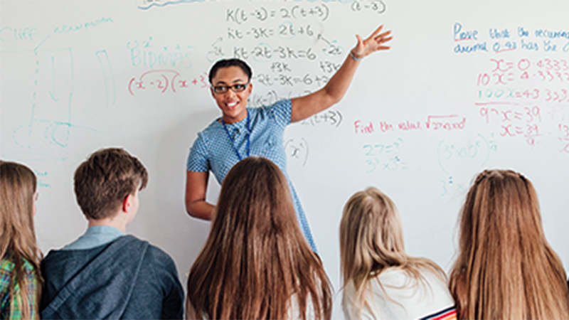 A woman standing in front of a whiteboard with math subjects written on it