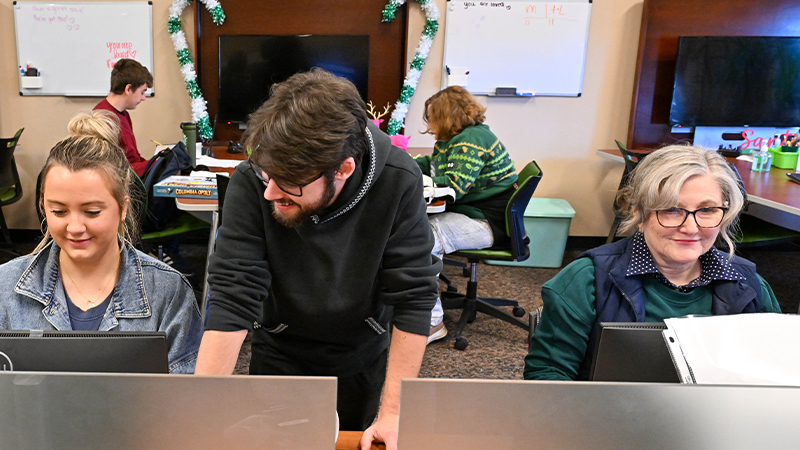 A group of students working on computers in a shared workspace.