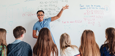 A woman standing in front of a whiteboard with math subjects written on it