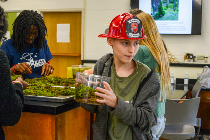 A STEM Within Reach student carries his self-sustaining ecosystem in a container.