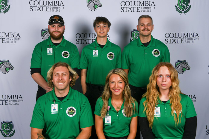 A group of people pose in front of a white background.