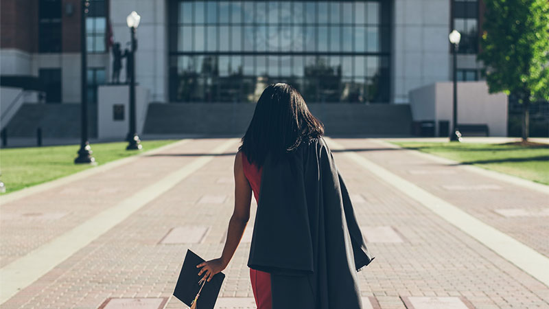 graduate walking toward college building