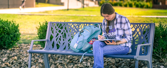 student sitting on bench outside